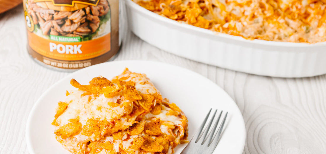 Pork enchilada casserole topped with melted cheese and crushed Chili Cheese Fritos beside a can of Keystone Pork